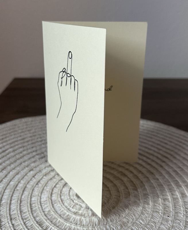 An actual middle finger card: a hand-drawn middle finger in ink on the front of a cream card