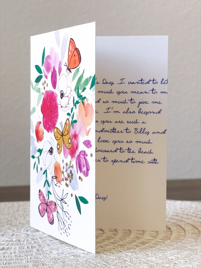 A Mother's Day card open on a table, showing a floral illustration and personal message inside